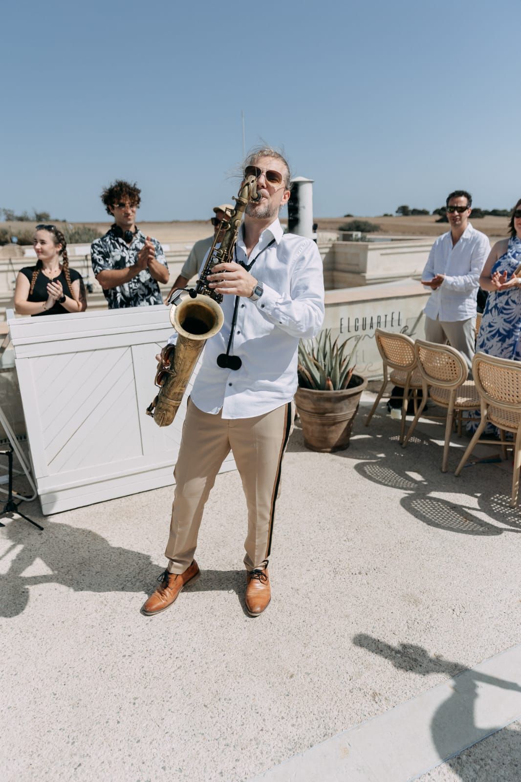 Saxophonist performing on a sunny rooftop terrace