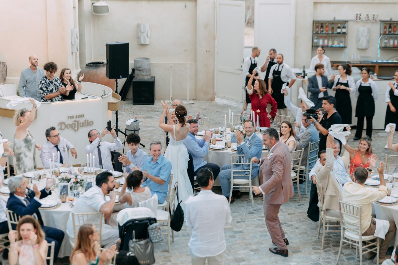 A couple dancing at an outdoor courtyard wedding reception while guests applaud