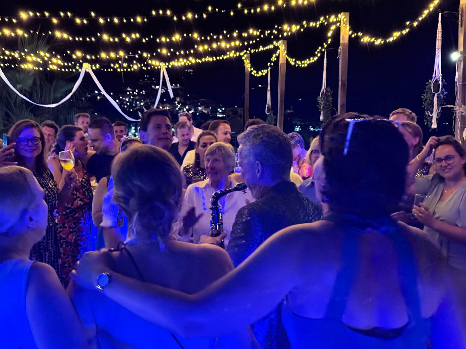 Guests dancing under string lights at a night-time celebration